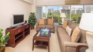 Ein modernes Wohnzimmer mit Flachbildfernseher, zwei Sofas, einem Couchtisch und einem großen Fenster mit Blick auf die Stadt.