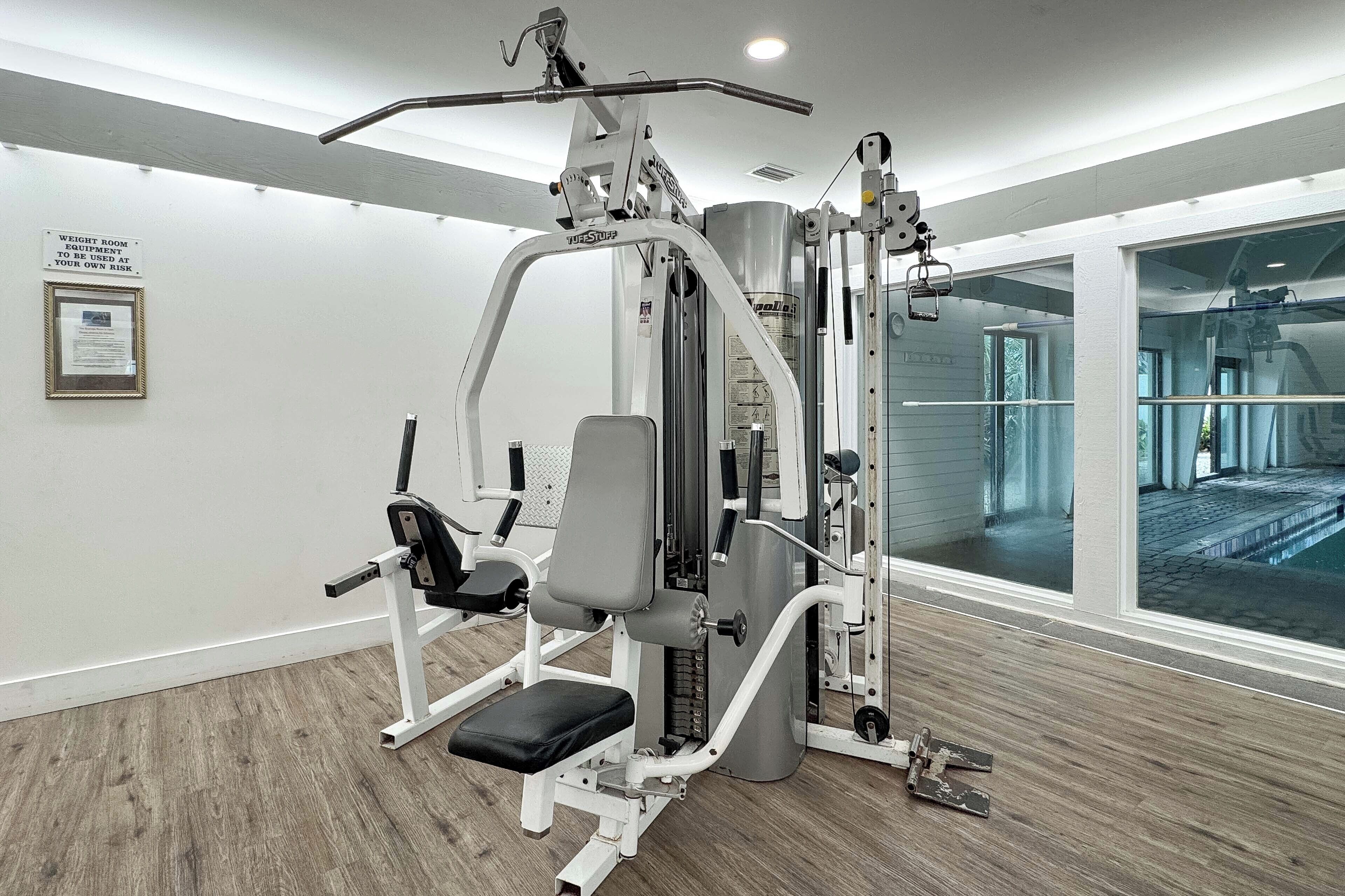 A gym with a weight room, equipped with various exercise machines and a large mirror.