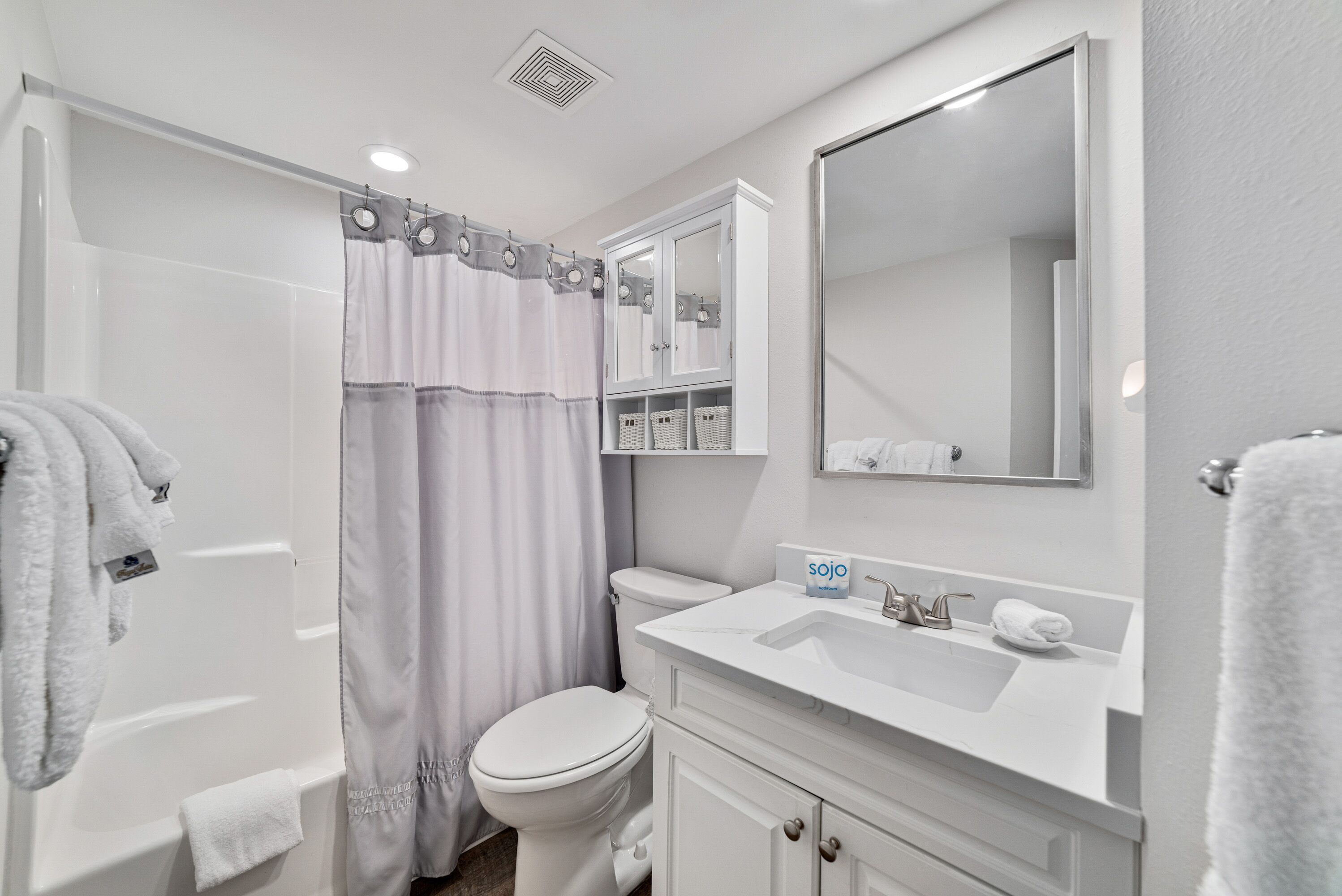 A modern bathroom with a bathtub, toilet, and vanity.