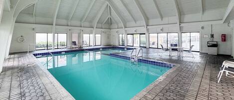 Una piscina interior con suelo de baldosas y techo abovedado.