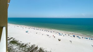 A beach with a clear sky, sandy shore, and umbrellas. - Summer House 1403B- Family friendly complex to enjoy the Beach!!! (Orange Beach)