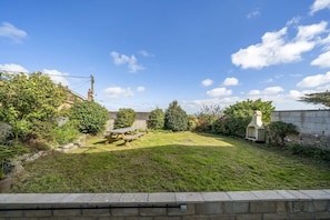 A backyard with a picnic table, a stone wall, and various plants.