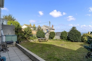 A residential backyard with a patio, a wooden table, and a barbecue grill.