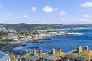 A coastal town with terraced houses, a beach, and a clear view of the sea.