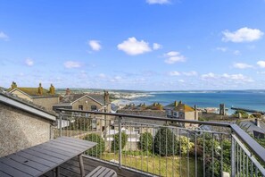 A balcony with a view of the sea and buildings.
