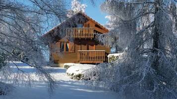 A wooden cabin with a balcony, surrounded by snow-covered trees.