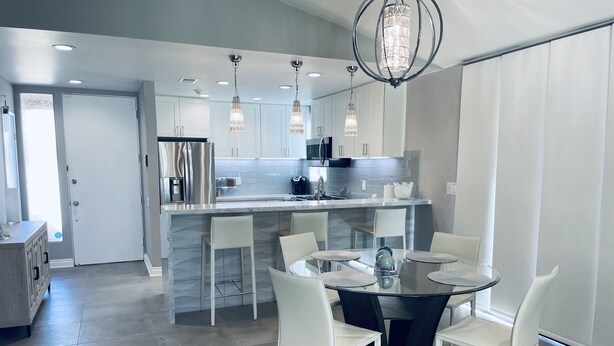 Een moderne keuken met witte kasten, een centraal eiland en hangende lampen.