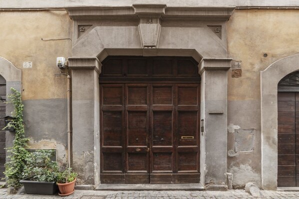 A large wooden double door with a metal handle, flanked by stone pillars and a decorative lintel.