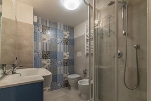 Une salle de bain avec douche, toilettes et lavabo.