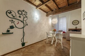 Un coin repas comprenant une table et des chaises, un luminaire fixé au mur et une horloge accrochée au mur.