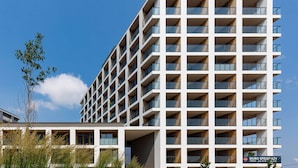 A modern multi-story building with a grid of balconies and large windows.