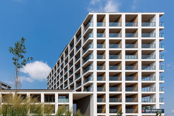 A modern multi-story building with a grid of balconies and large windows.