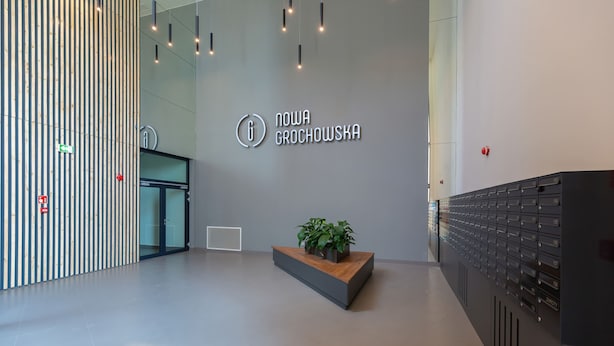 A modern reception area with a vertical wooden panel design, a plant centerpiece, and a row of black lockers.