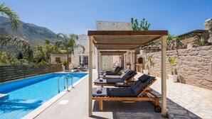 A poolside area with lounge chairs, a pergola, and a stone wall. - Casa Belvedere Boutique Villa (Apokoronas)