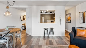 Un salon moderne comprenant un coin repas, une cuisine et un grand miroir.