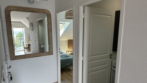 A hotel room with a large mirror, a bed with a green bedspread, a small table, and a chair. - Apartment sea view 🌊 south facing ☀️à Carantec (Carantec)