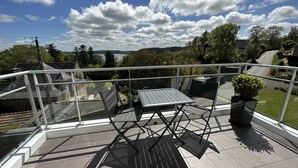 A balcony with a table and chairs, a potted plant, and a view of a road and trees. - Apartment sea view 🌊 south facing ☀️à Carantec (Carantec)