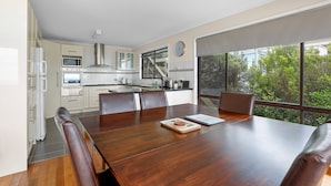 A modern kitchen with white cabinets, stainless steel appliances, and a large window overlooking greenery. - Marengo Panoramic Ocean Views (Marengo)
