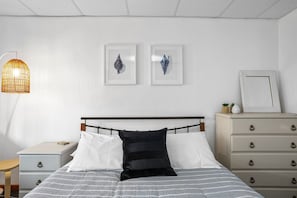 A bedroom with a bed, bedside tables, a dresser, and wall art. - Marengo Panoramic Ocean Views (Marengo)