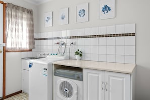 A laundry room with a washing machine, a dryer, a sink, and a small potted plant. - Marengo Panoramic Ocean Views (Marengo)