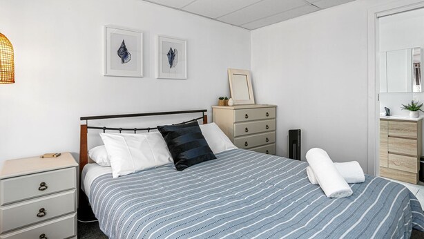 A bedroom with a bed, a nightstand, a dresser, a mirror, and two framed pictures on the wall. - Marengo Panoramic Ocean Views (Marengo)