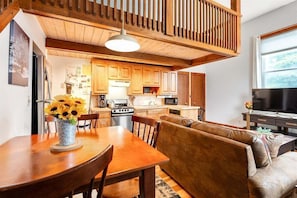 A wooden interior with a dining table, sofa, and kitchen area.