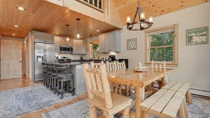 A spacious kitchen with wooden cabinets, a stainless steel refrigerator, and a dining area with a wooden table and chairs.