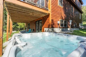 A wooden building with a hot tub and a covered patio area.