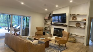 Uma sala de estar moderna com sofá, poltronas, mesa de centro, lareira e televisão.