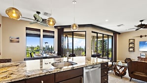 A modern kitchen with a large island, dark cabinetry, and a view to the outdoors. - Luxury Kapalua Golf Villa With Beautiful Sweeping Views (Lahaina)