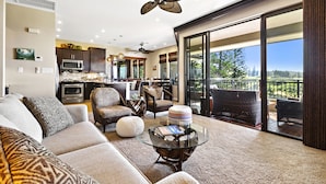 A spacious living area with a large glass table, comfortable seating, and a ceiling fan. - Luxury Kapalua Golf Villa With Beautiful Sweeping Views (Lahaina)