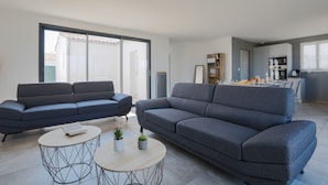 A modern living room with two sofas, a coffee table, and a kitchen area in the background. - Equiped house for 4 adults and 4 children (Le Bois-Plage-en-Ré)