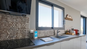 A modern kitchen with a large window, patterned backsplash, and a countertop with a box of tissues and a red appliance. - Equiped house for 4 adults and 4 children (Le Bois-Plage-en-Ré)