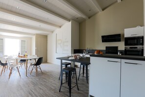 Une cuisine moderne avec des meubles blancs, un plan de travail noir et un îlot central doté de tabourets.