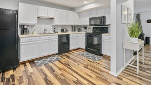 A modern kitchen with white cabinets, a black refrigerator, a microwave, and a stove. - GannonHeights: Work-Friendly & 40 mins to DC (Sterling)