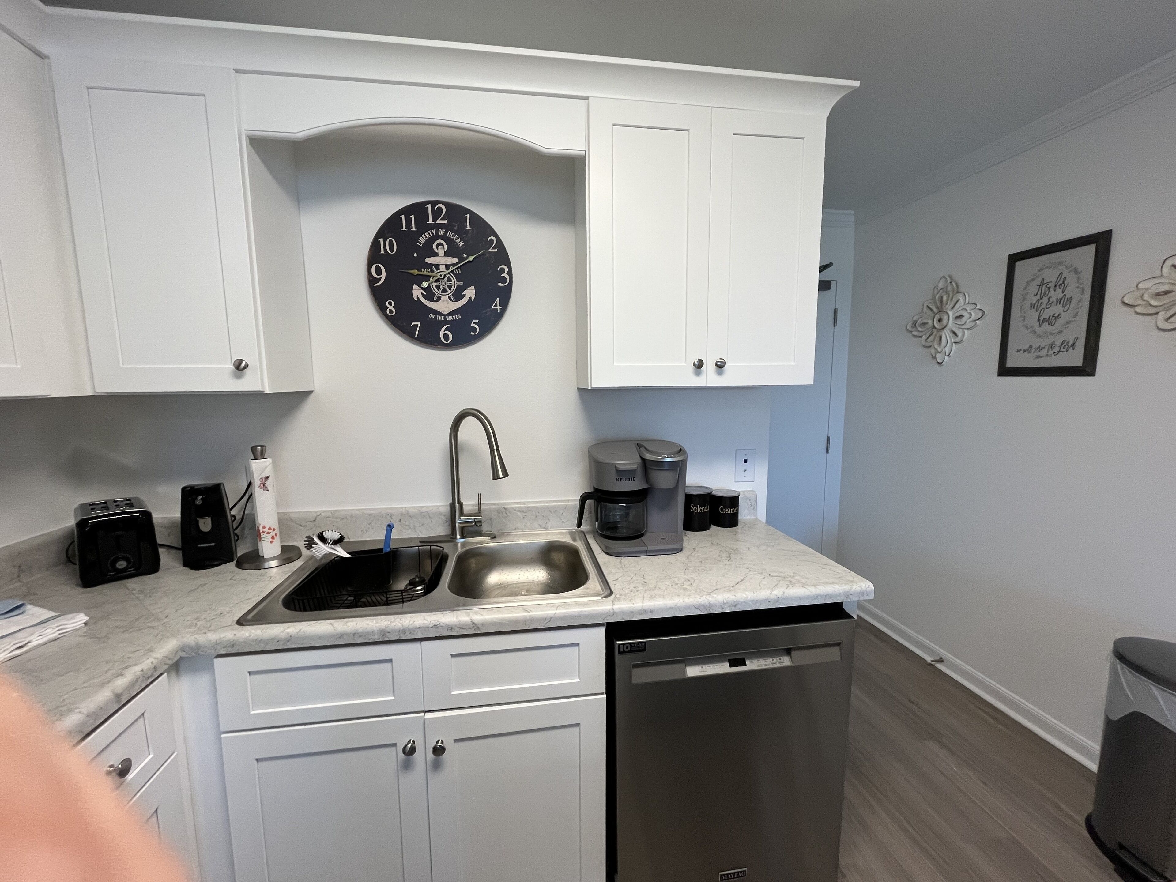 A kitchen with white cabinets, a stainless steel sink, a coffee maker, and a dishwasher.