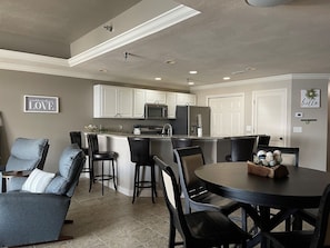 A modern kitchen with white cabinets, a central island, and a dining area with a round table and chairs. - 6109 Towers, Beautiful Condo! Quiet! Elevators, indoor/outdoor pools. Free Wifi (Osage Beach)