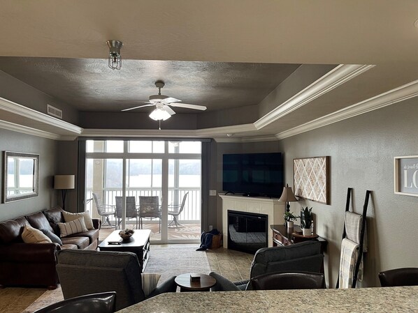 A living room with a fireplace, a television, and a balcony with outdoor seating.