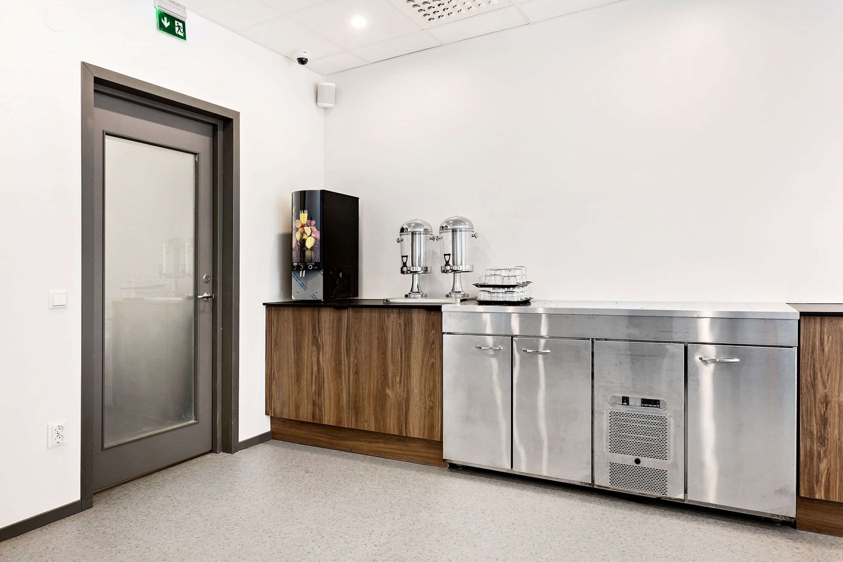 Una cocina moderna con electrodomésticos de acero inoxidable, un armario de madera y una puerta de vidrio esmerilado.