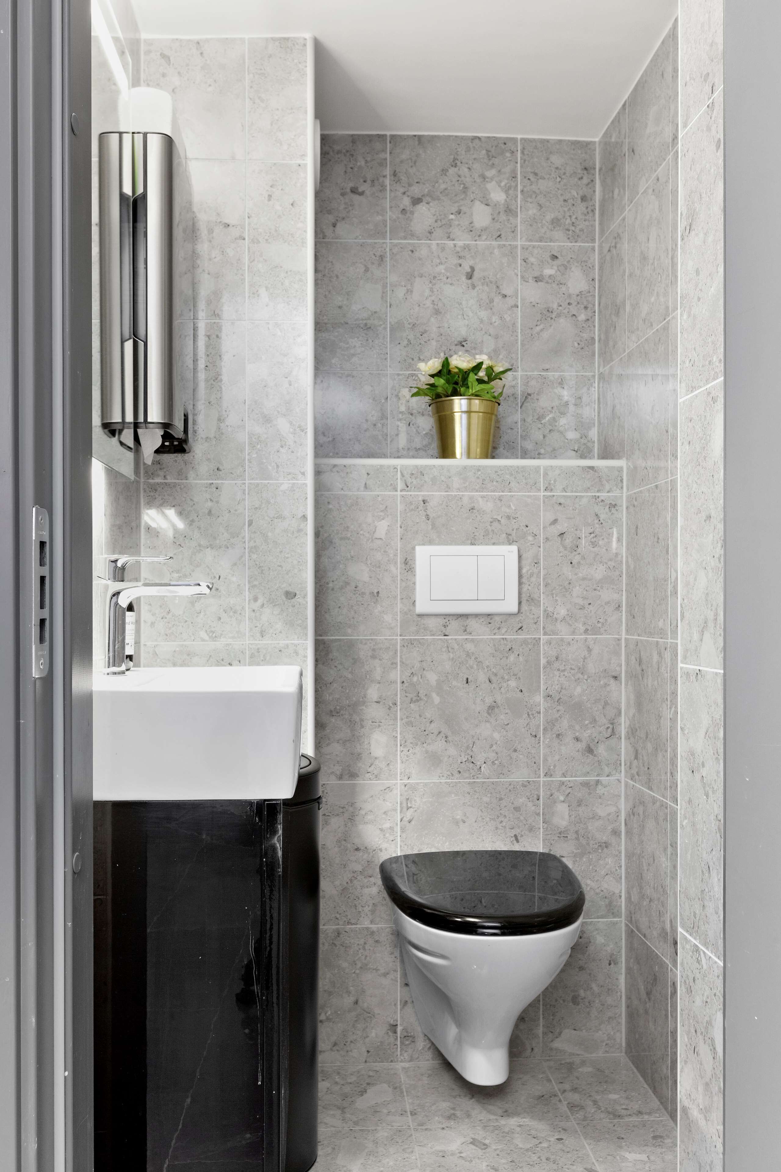 A modern bathroom with a white sink, a black toilet, and a shower area.
