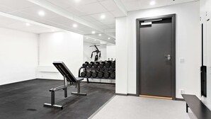 Une salle de sport équipée d’un banc, d’haltères et d’un support à squats.