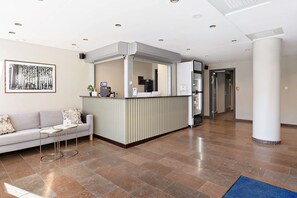 A reception area with a sofa, a small table, a counter, and a framed picture on the wall. - Sure Hotel Studio by Best Western Bromma (Bromma)
