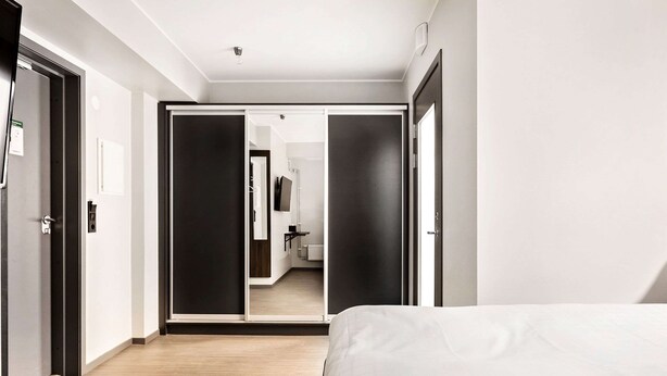 Une chambre d’hôtel moderne avec un grand lit, une armoire et un miroir.