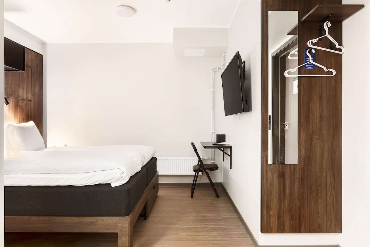 Une chambre à coucher comprenant un lit, un bureau, une chaise, un téléviseur et une armoire.
