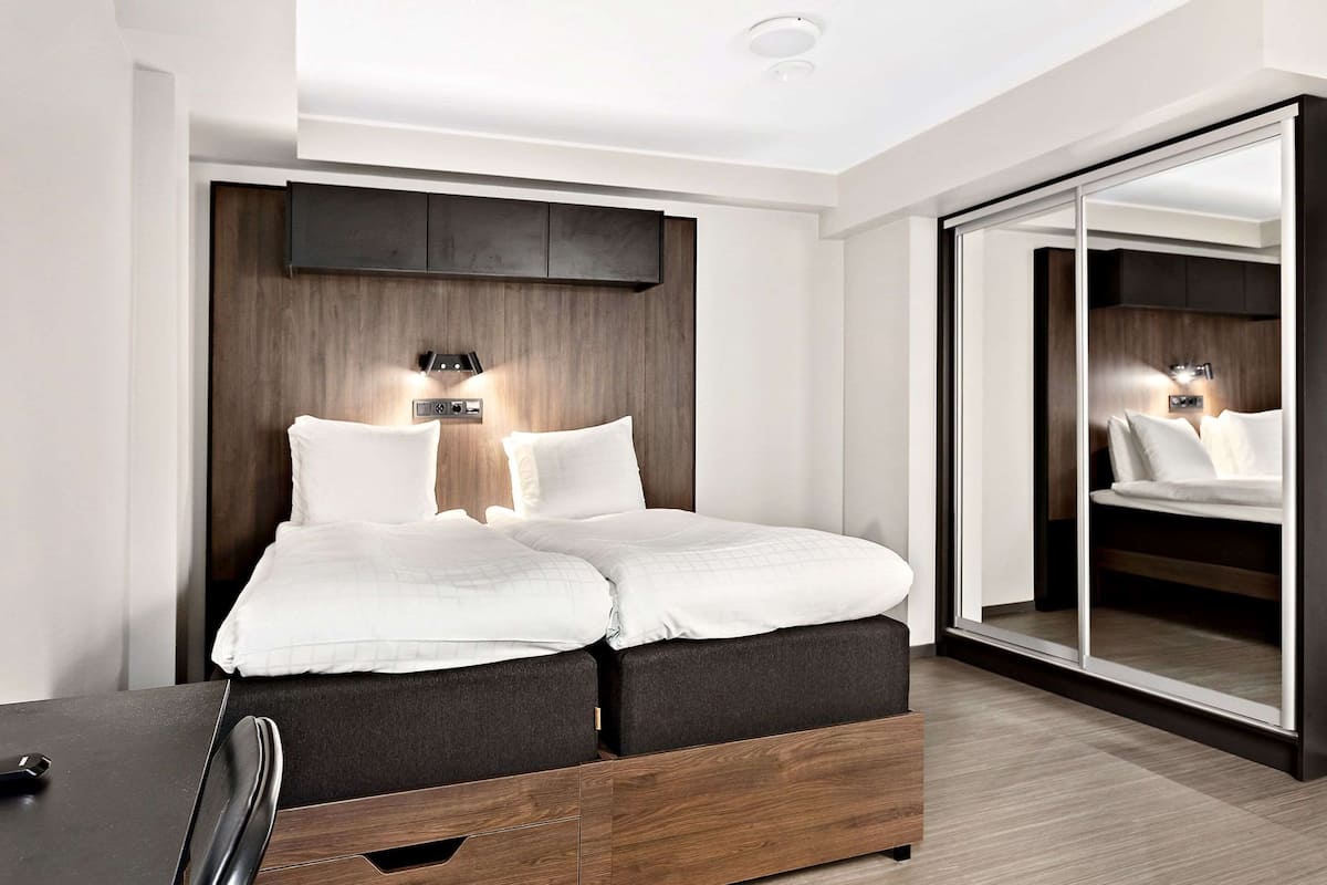 Une chambre moderne comprenant un lit, des tables de chevet, une armoire et un placard à portes coulissantes.