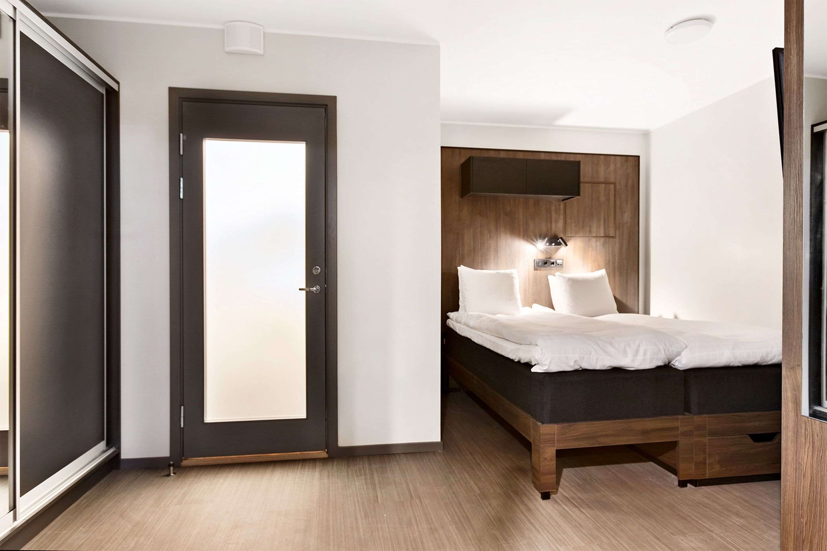 A bedroom with a bed, a wardrobe, and a door.