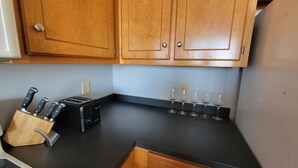 A kitchen with wooden cabinets, a black countertop, a toaster, and a knife block. - Inn at Dauphin Island 306 Efficient 1BR sleeps 6 with Beautiful Views!! (Dauphin Island)