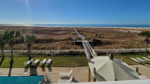 A beach view from a resort with a wooden boardwalk, lounge chairs, and a pool. - Inn at Dauphin Island 306 Efficient 1BR sleeps 6 with Beautiful Views!! (Dauphin Island)