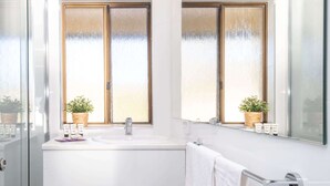 Ein Badezimmer mit zwei Waschbecken, Milchglasfenstern und Zimmerpflanzen.