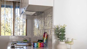A modern kitchen with a window, a sink, and a decorative plant. - Seafront Getaway Studio, Great Location with Pool (Batemans Bay)
